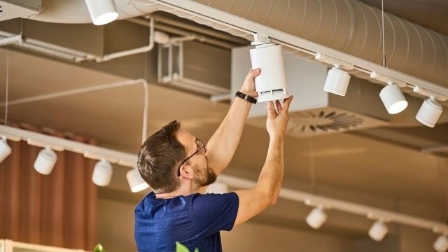 Installazione di diffusori wireless SpotTune su binario luce a soffitto in un locale